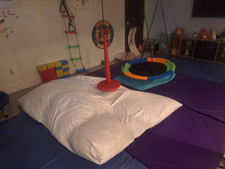 Colorful sensory play room with rainbow trampoline and climbing equipment